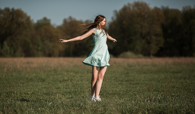 boost your confidence by getting outside woman in field with wind blowing hair and dress