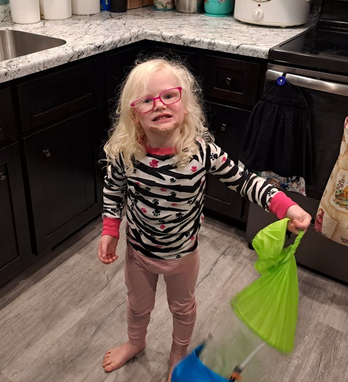 little girl wearing glasses holding the saladzilla salad spinner in the kitchen