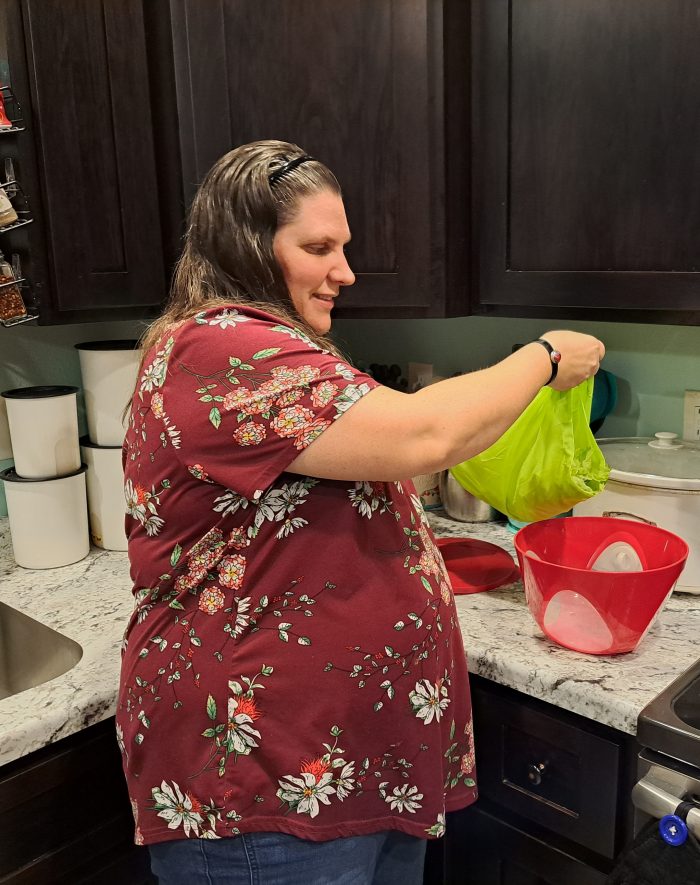 smiling woman about to pour lettuce leaves out of the saladzilla salad spinner in her kitchen