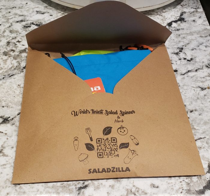 kraft paper envelope open to reveal a blue material with a product tag for saladzilla