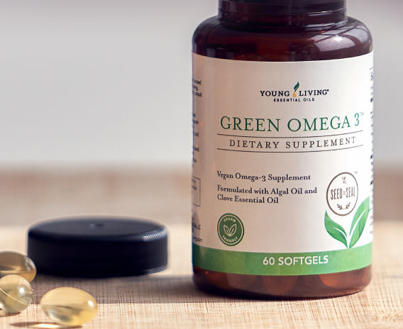 Young Living's Green Omega 3 Dietary Supplement with softgels laying next to bottle and cap