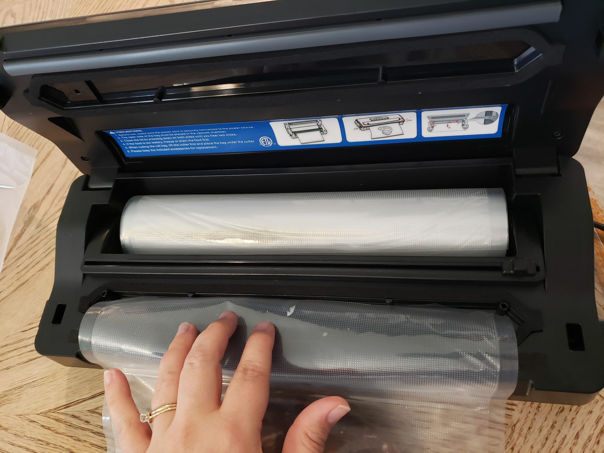 inkbird plus vacuum sealer with fingers holding a bag up to the vacuum section