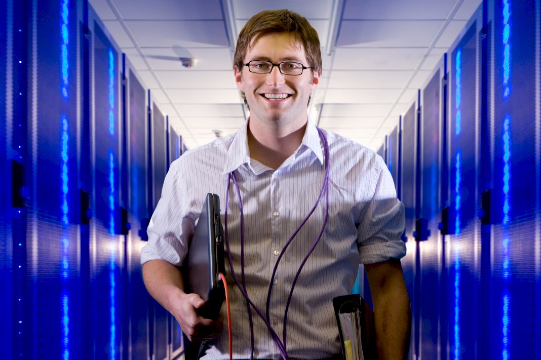 smiling tech support guy carrying a manual laptop and wires coming to help when it downtimes affect business