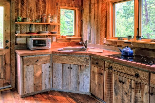 new home kitchen that looks traditional with barn wood cupboards and wood walls and floors tea pot on stove top