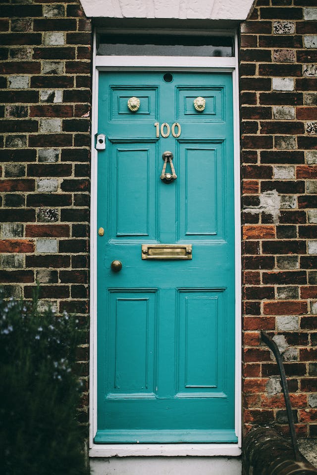 teal door on front of a brick house