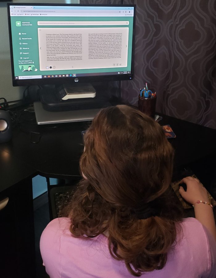 teen girl looking at monitor reading an online book with beige colored page and black lettering