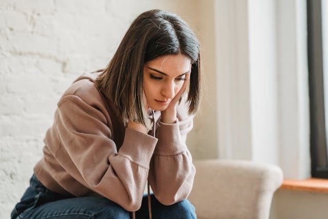 sad woman with hands on face looking downcast