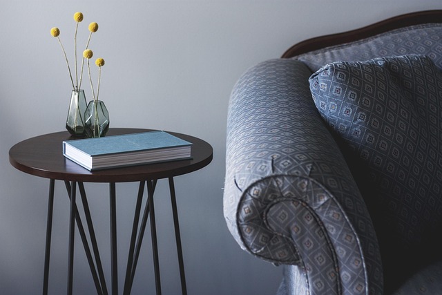 one end of a couch next to end table with book and glass vases with yellow flowers