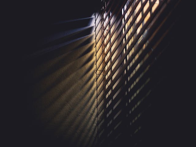 blinds showing a tiny bit of light in a dark room