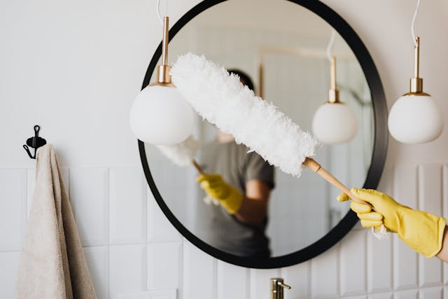 Too much to do? Let us help you choose the best cleaning company for your home. This will help you feel less overwhelm and more in control. person cleaning light fixture with duster wand in bathroom