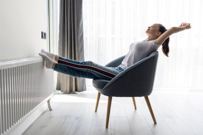 woman stretching in a chair with feet on the radiator