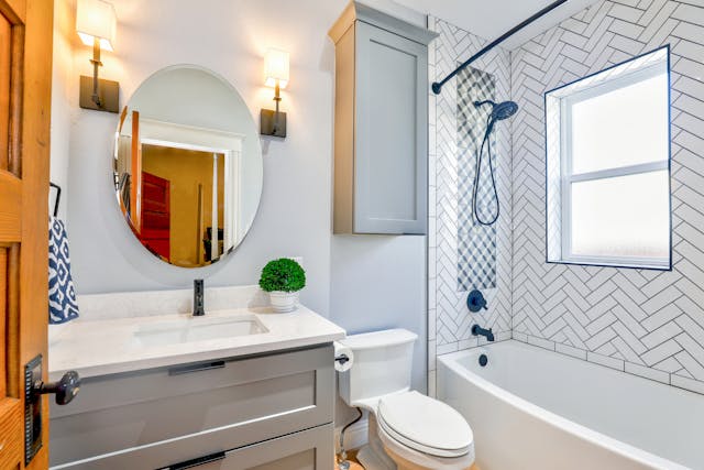 bathroom with an oval mirror tub shower combo and wall cupboard above toilet