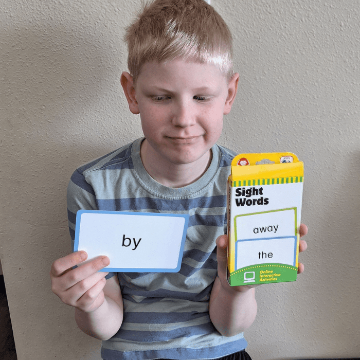 boy holding sight words flash cards box and a word card by