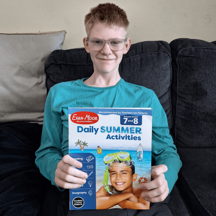 teen boy holding evan moor daily summer activities workbook grade 7 and grade 8