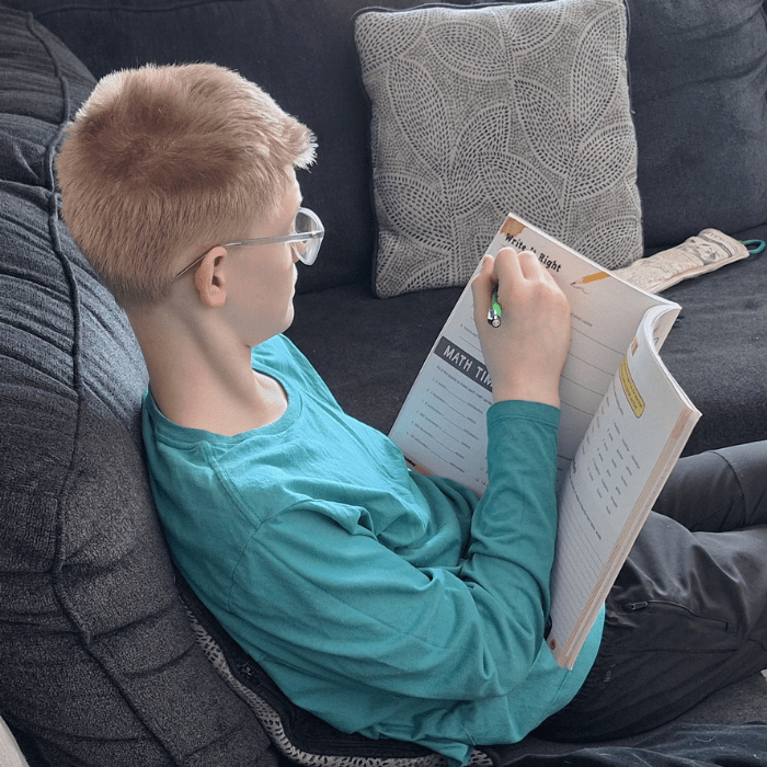 teen boy writing in a workbook math page