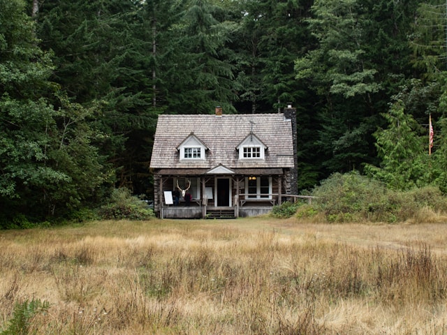 house near woods large trees prairie grass in front