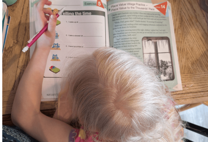 girl with pencil in her hand about to write the answer in her math workbook