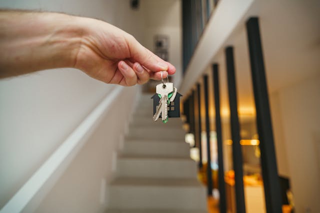 To buy your first home as a single person, here are a few handy tips to help make the process of buying your first home easier. keys held before a stairway