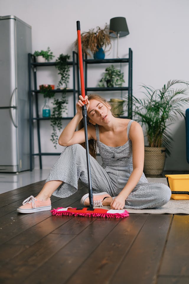exhausted woman on floor with mop in hand