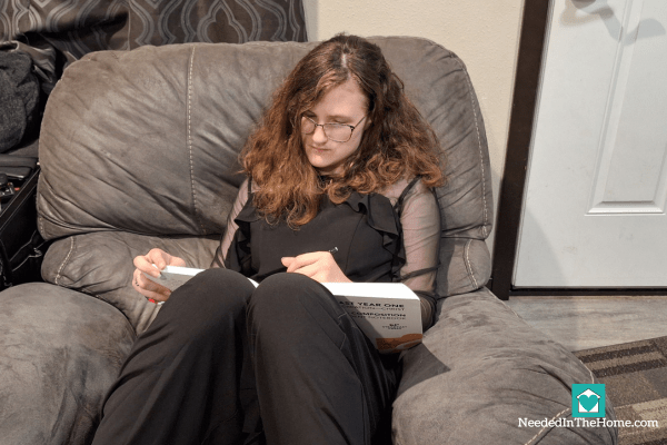 teen girl writing in her steadfast year one literature and composition student notebook while reclining in a rocking chair