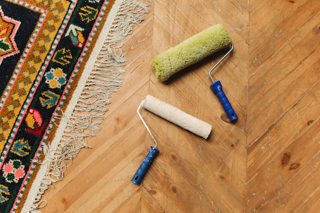 two paint rollers on hardwood floor next to rug