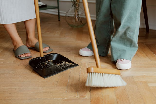 two peoples feet with broom and dustpan