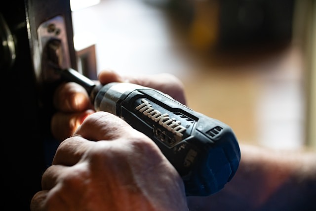mans hand using a makita drill to replace door lock