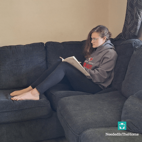 teen girl sitting on couch and writing in her art journal
