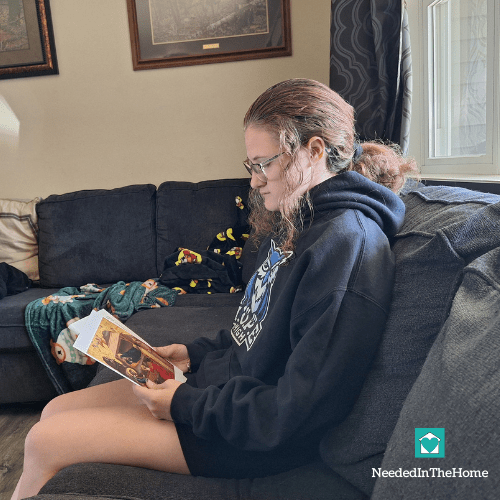 teen girl looks seriously at an art card with a sample of an artists work