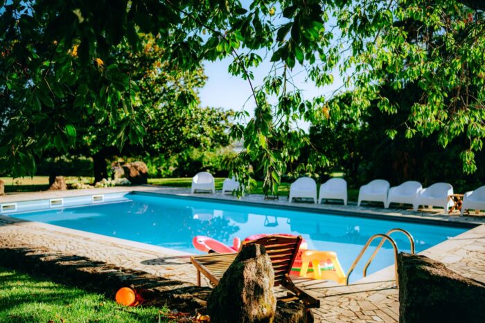 backyard swimming pool with deck chairs and inflatables
