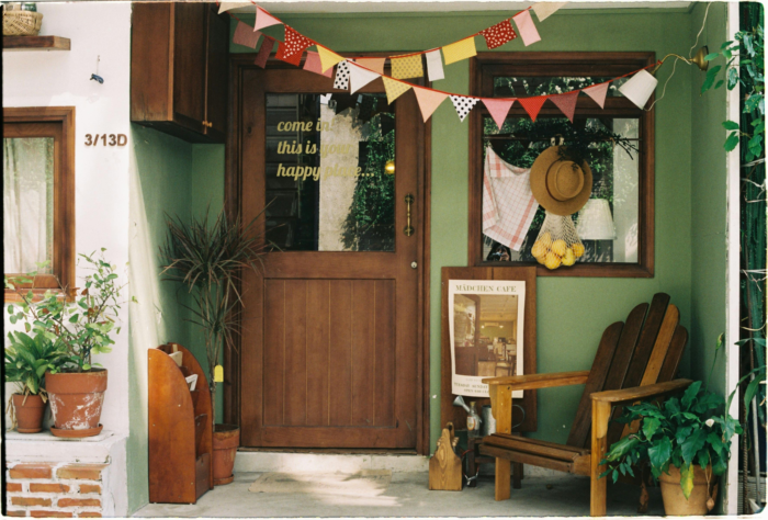 It's so much better to live in an enjoyable environment. These tips will help you to make your home a happy, livable place. home front exterior with festive porch decor chair plants wording on window