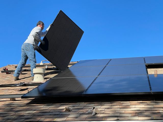 man on roof with a solar panel