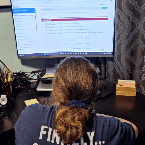 This is our product review of the Axiom Science High School Chemistry online course with 191 videos, 50 self-grading quizzes, and 20 Labs. teen girl with ponytail looking at her chemistry course on the computer screen about solubility