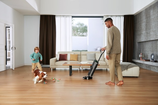 Your indoor air quality inside your home can actually be much more polluted than the air outside. Here's what to do. man with vacuum on floor near dog and child in living room
