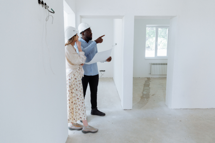 woman and man with hard hats on discussing renovations in a home