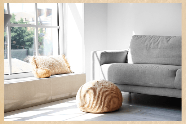 You need to make your home cozy so that you can return to in the evening and feel a genuine sense of well-being. living room couch with pillow near window and pouf on floor