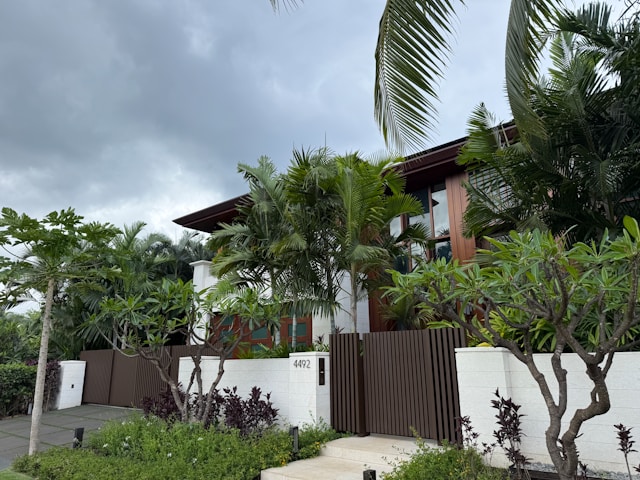 large home with fenced in front yard and palm trees