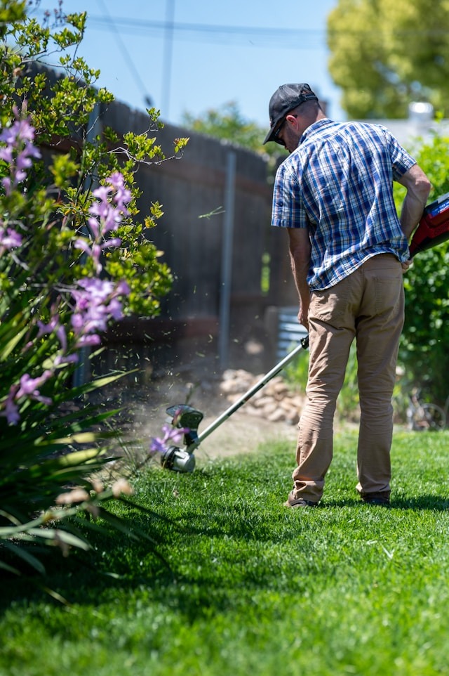 man weed whacking his backyard