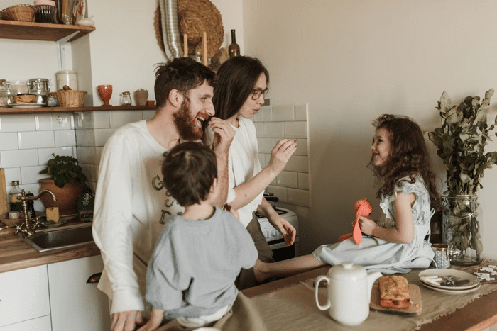 You can keep your family safe around gas appliances by teaching children that gas appliances aren’t play areas, even when switched off. family in a kitchen with kids sitting on the counter near parents